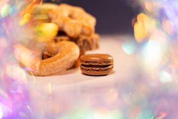 Vibrant macarons, cookies, and gingerbread on a white surface against a black backdrop, accented by...