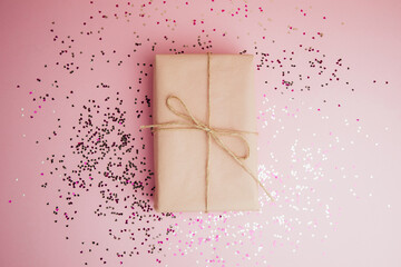 Background for greetings. Gifts wrapping in soft pink paper on a light pink background with sequins...