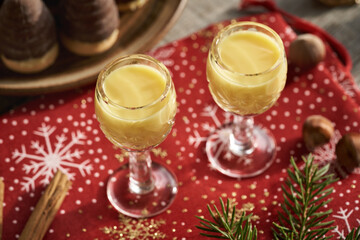 Creamy eggnog in two glasses with Christmas cookies and decoration