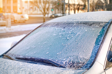 Windshield covered with ice, frozen glass and wiper. Car window under layer of ice. Frost on car glass. Low visibility, dangerous driving in winter season. - obrazy, fototapety, plakaty