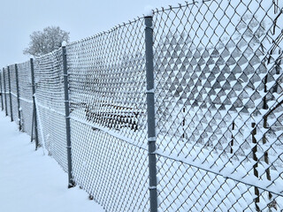 room paint rollers are fixed on a snowy fence. frozen wire mesh of the logistics area