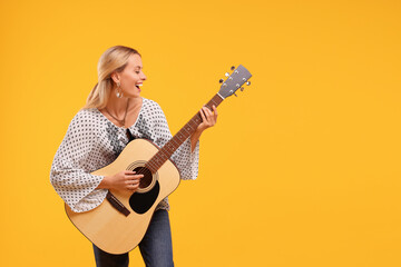 Happy hippie woman playing guitar on yellow background. Space for text