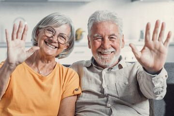 Sixty years couple, elderly parents communicates with grown up children using modern technologies makes video call, wave hands gesture of hello or goodbye sign, older generation and internet concept. - obrazy, fototapety, plakaty