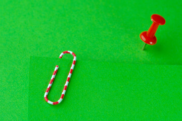 Red paperclip and red button on green blank sheets