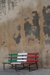 A bench in the colors of the Italian flag by the church wall