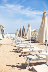 Beach on a summer day with sun beds and umbrellas by the seashore