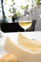 Yellow melon slices, a peach and a glass of sparkling wine on a sunny summer day