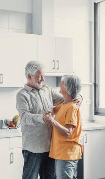 Joyful Active Old Retired Romantic Couple Dancing Laughing In Living Room, Happy Middle Aged Wife And Elder Husband Having Fun At Home, Smiling Senior Family Grandparents Relaxing Bonding Together.