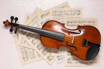 Violin and music sheets on white wooden table, top view