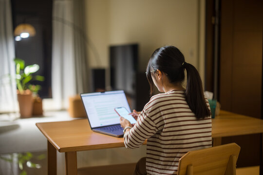 Woman work form home with laptop and use of mobile phone in the evening