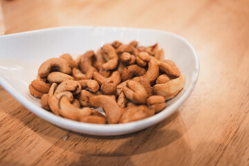 Tasty cashew nuts in white bowl on a wood table. Food concept.