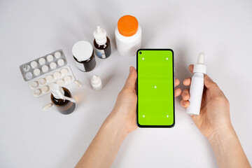 Green screen chroma key smartphone in the hands of patient or doctor and a lot of medicines....