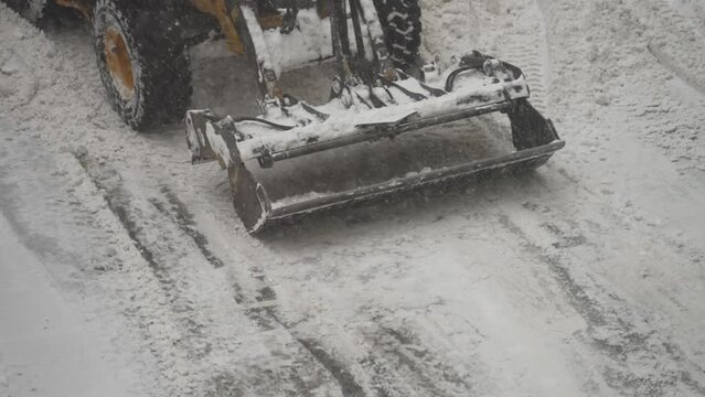 Tractor shoveling snow on the street.