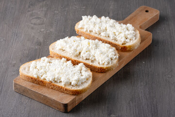 Bread with curd cheese on wooden board