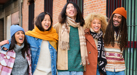 Group of five multiracial friends laughing and walking along the street in autumn.