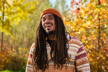 African American young man with dreadlocks laughing and looking at camera in a sunny day of autumn.