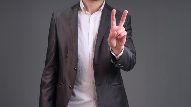 Radiate positivity and good fortune with this uplifting stock video capturing a moment of optimism as a man raises two fingers in a V gesture. The scene opens with a dynamic close-up, focusing on the 