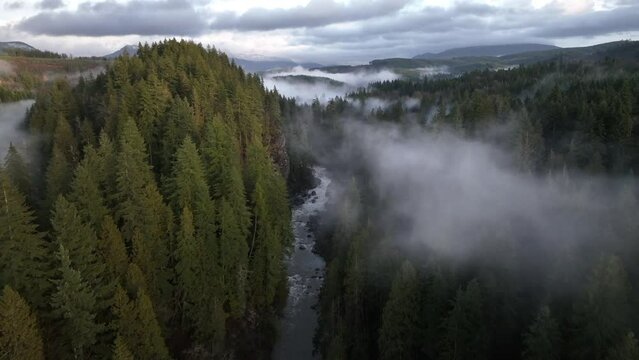 Aerial view of Granite Falls during sunset Clouds above forest in Pacific Northwest, drone shot of trees and fog