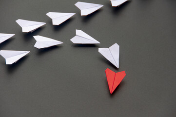 Red paper plane origami leading white planes on dark background. Leadership skills concept