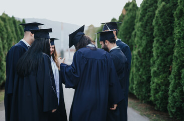 Diverse faculty students celebrate success outdoors in graduation gowns and caps, sharing happiness...