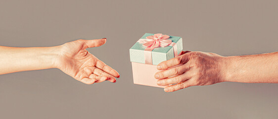 Gift box in hand, surprise and holiday concept. Man hands holding valentines day gift. Girl gives a...