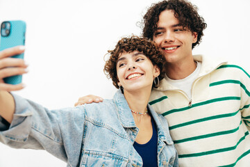 Smiling beautiful woman and her handsome boyfriend with curls hairstyle. Happy cheerful family having tender moments in white interior in studio.Pure cheerful models hugging. take selfie photos