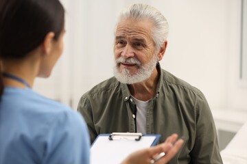 Elderly patient talking with nurse in hospital