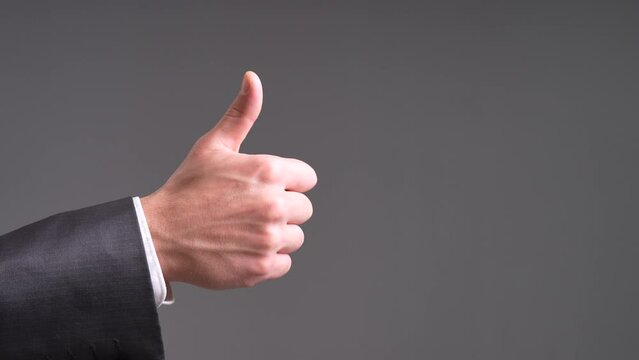 Radiate positivity and approval with this uplifting stock video capturing a man confidently giving a thumbs-up signal. The scene opens with a dynamic close-up, focusing on the man's hand as he extends