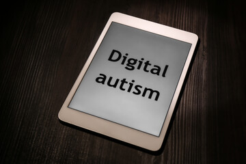 Tablet with phrase Digital Autism on wooden table. Addictive behavior