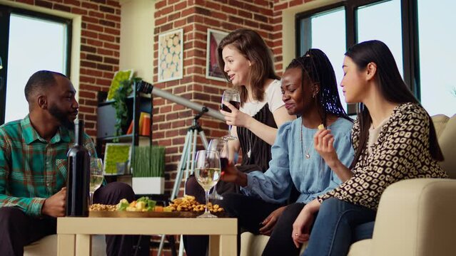 BIPOC coworkers celebrating business success at work, gathered at home to toast for their accomplishments. Cheerful colleagues throwing apartment party, drinking wine glasses