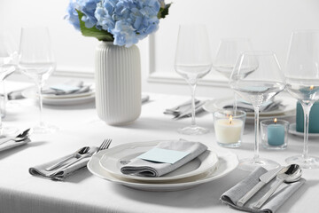 Beautiful table setting with card and floral decor indoors