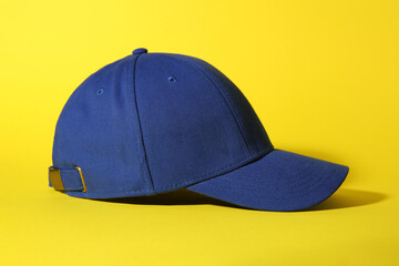 Stylish blue baseball cap on yellow background