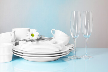 Set of clean dishes, glasses and cutlery on light blue table