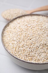 Raw barley groats in bowl on light table, closeup