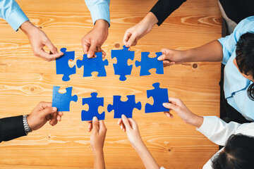 Top view multiethnic business people holding jigsaw pieces and merge them together as effective...