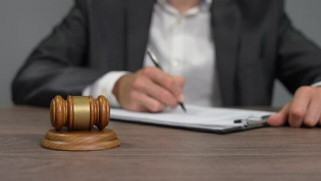 Enter the solemn ambiance of the courtroom with this compelling stock video capturing a pivotal moment as a judge meticulously writes and delivers a verdict. The scene unfolds with a close-up view of 