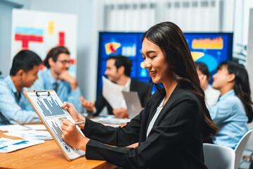 Portrait of happy young asian businesswoman or analyst looking at camera with her colleague...