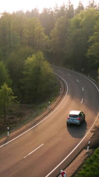 convertable car in sunny nature on a bright summer day. wide angle pursuit shot - vertical video for reels and story