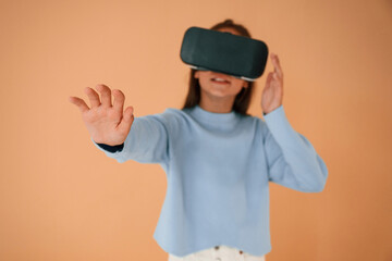 Trying VR glasses. Cute young girl is in the studio against background