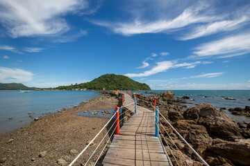 Obraz premium The wooden bridge with rail bridge made from rope to go to the viewpoint to see the white pagoda stay on the stone in the middle of the see at Baan Hua Laem, Chanthaburi, Thailand.