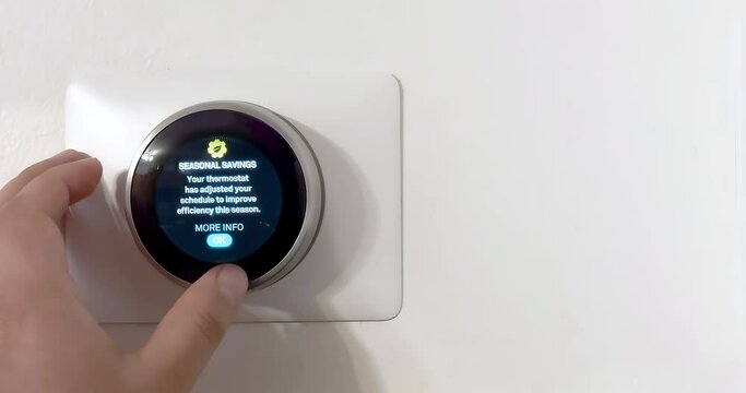 A person saving energy with a smart thermostat that adjusted schedule to improve efficiency during winter season.