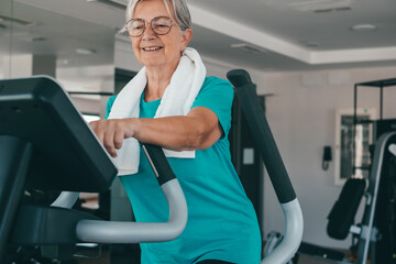 Attractive smiling retired woman excercising on stepper at gym to stay fit. Cardio excercises for...