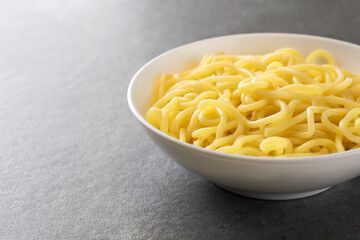Soup ramen noodles in ceramic bowl on a gray background.