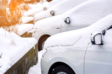 Car after snow sorm. Cars buried in snow. Parked cars covered with snow, winter parking lot..