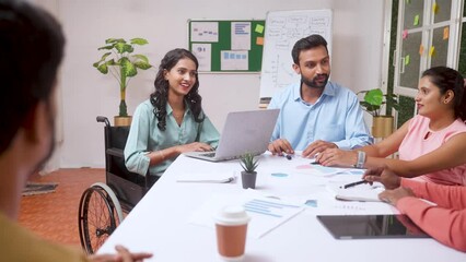 woman with disability on wheelchair getting applause from team or co-workers during for presentation at meeting - concept of encouragement, inspiration and startup culture