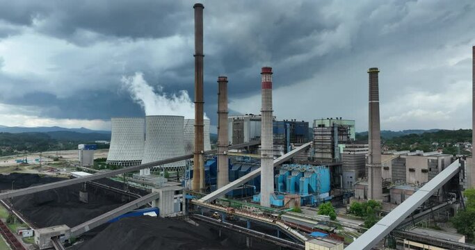 Aerial drone footage of a large coal power plant station with cooling towers chimney and boiler house in an air pollution or carbon footprint concept