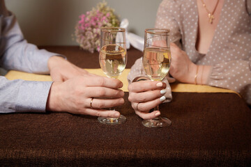 Hands Man and woman sitting at a table with glasses of champagne. Hands with rings on the fingers. Newlyweds and divorce. Quarrel, swearing, hatred, holiday, wedding, newlyweds