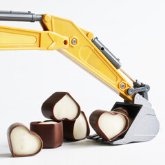 Toy excavator bucket with heart-shaped chocolates. Concept of mining and choosing a love partner,...
