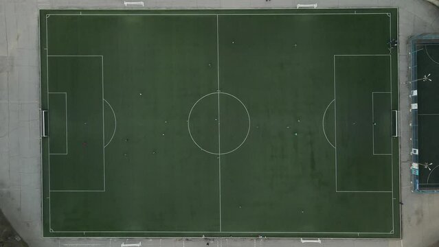 Aerial top view by drone of mini football soccer field with playing people.