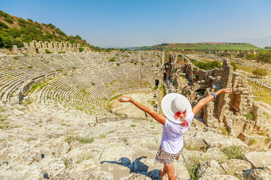 tourist woman visiting the ancient Roman Theatre in Perge, Turkey, an impressive testament to the architectural achievements of antiquity. Dating back to the 2nd century AD.